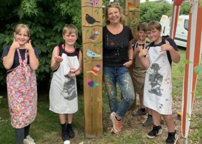 Artist Sarah Hodgkins with children painting a buird mural onto sleepers