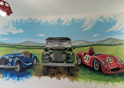 Mural of a blue morgan car, a land rover and a red vintage race car