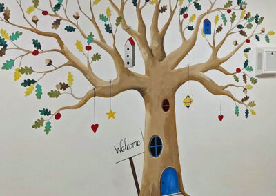 Stylised tree mural with bird boxes and welcome sign